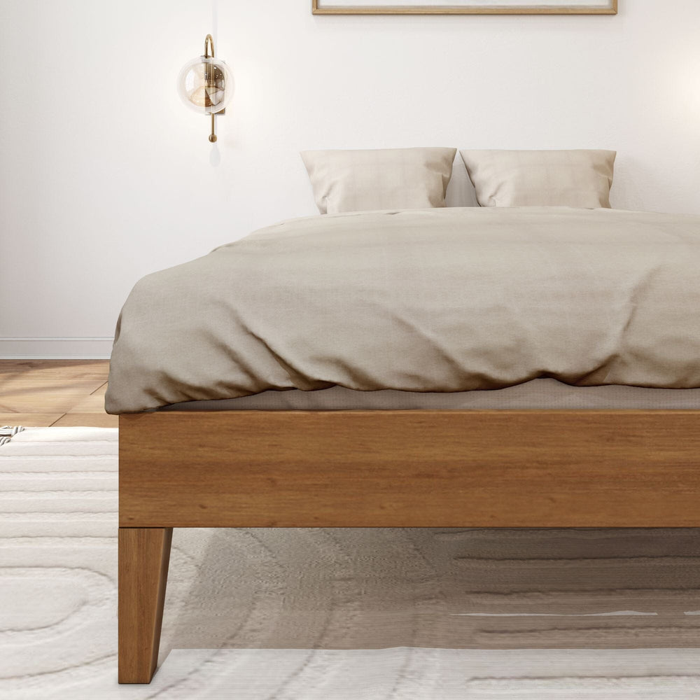 Full Size Platform Bed Pecan Leg Detail Full Size Platform Bed in Pecan - close-up of the low side rail and tapered wooden leg under the beige duvet