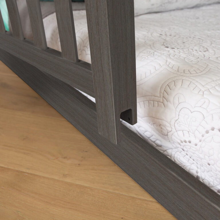 Max and Lily Add on Safety Guard Rail in Clay - close-up of the rail's lower mounting bracket attaching to the bed frame beside the mattress.