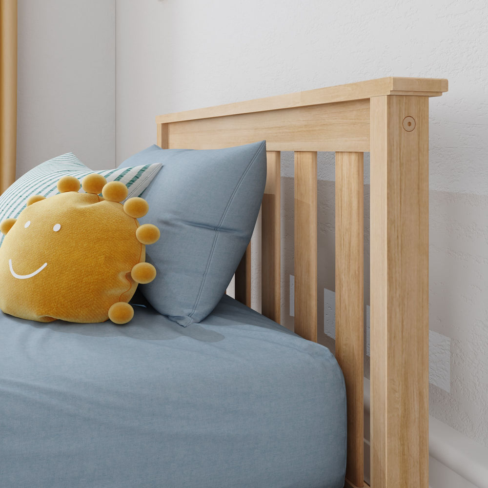 Max and Lily Classic Twin Floor Bed in Blonde - close-up of the slatted headboard with a blue pillow and sun-shaped cushion