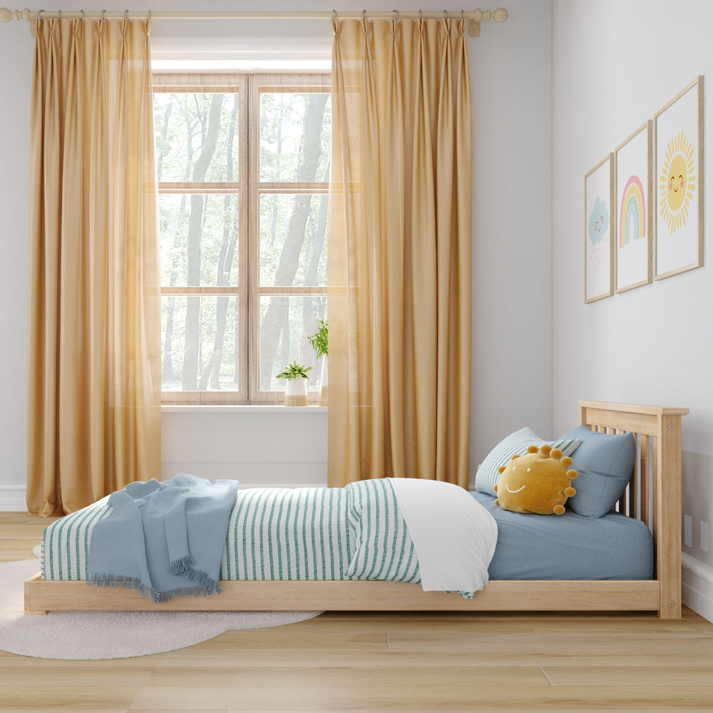 Max and Lily Classic Twin Floor Bed in Blonde - shown in a child's room beside a window with yellow curtains and blue striped bedding