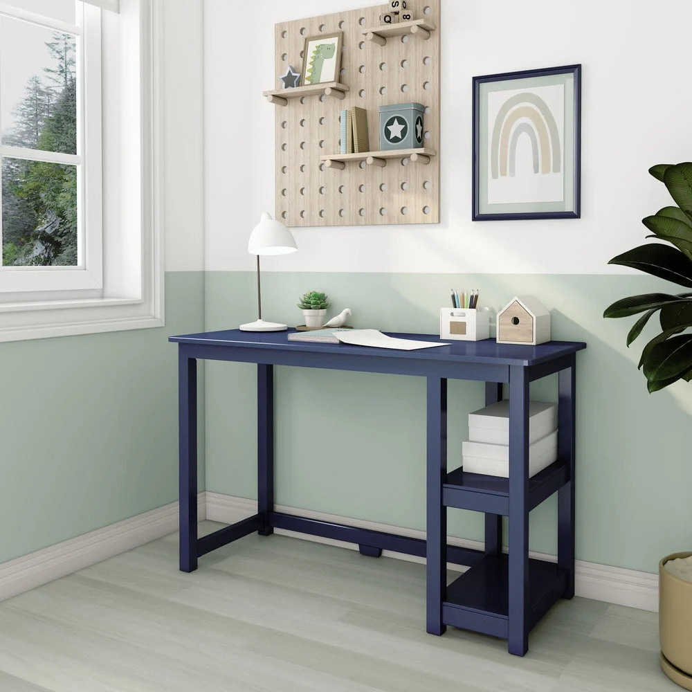 Max and Lily Desk With Shelves in Blue - room scene by a window with the desk styled with a lamp and open shelves.