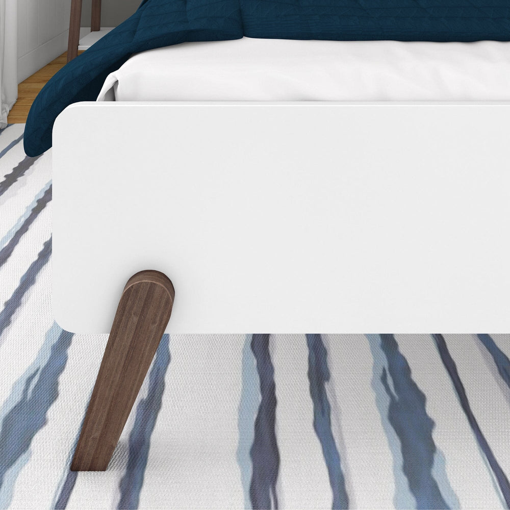 Max and Lily Mid-Century Modern Full Bed - closeup of the footboard panel and angled solid wood leg over an area rug
