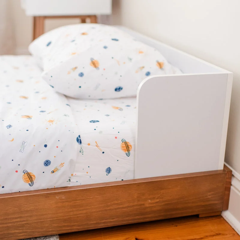 Max and Lily Mid-Century Modern Twin Floor Bed in White/Pecan - closeup of the rounded white headboard panel above the wood base with space-print bedding