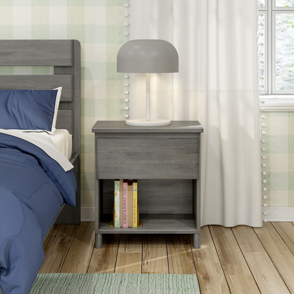 Max And Lily Modern Farmhouse Night Stand Driftwood Room Scene 2 Max and Lily Modern Farmhouse Night Stand in Driftwood - shown beside a bed with a lamp on top and books stored on the open lower shelf.