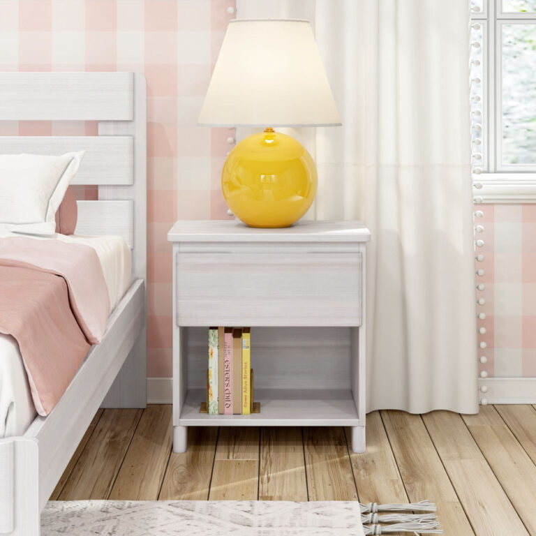 Max And Lily Modern Farmhouse Night Stand White Wash Room Scene 2 Max and Lily Modern Farmhouse Night Stand in White Wash - placed next to a bed near a curtained window with a yellow lamp and books on the lower open shelf.