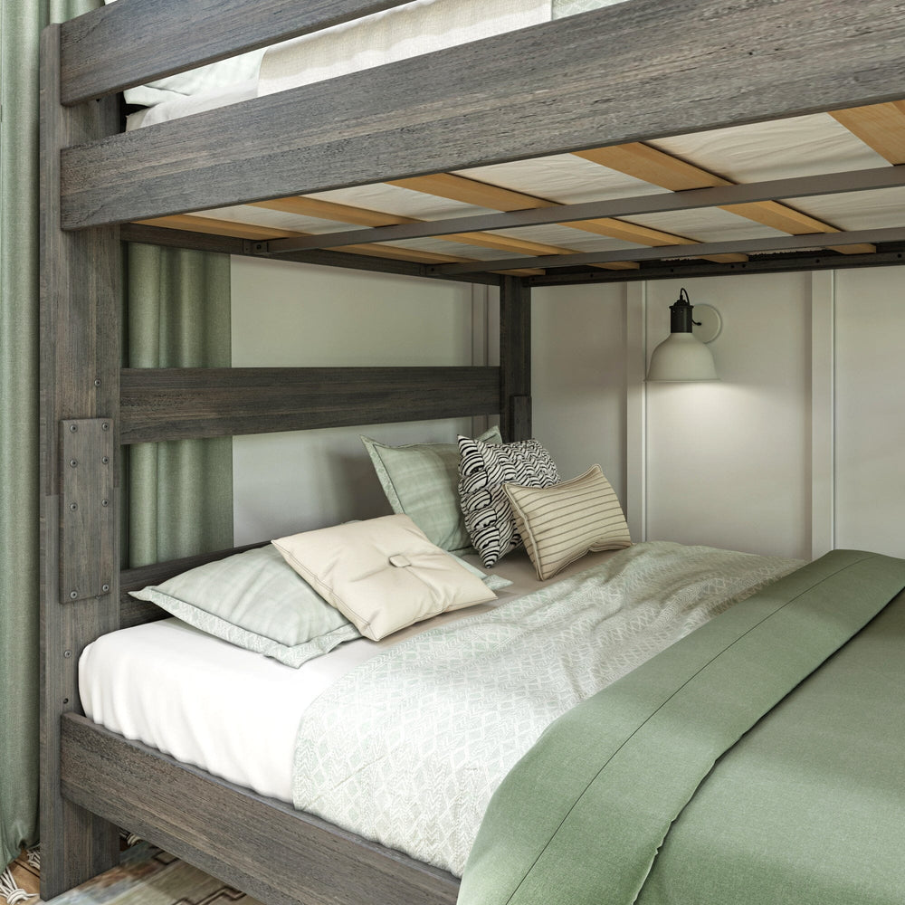 Max and Lily Modern Farmhouse Queen Over Queen Bunk Bed in Driftwood - close-up of the lower bunk styled with sage green and cream pillows beside a lit wall sconce