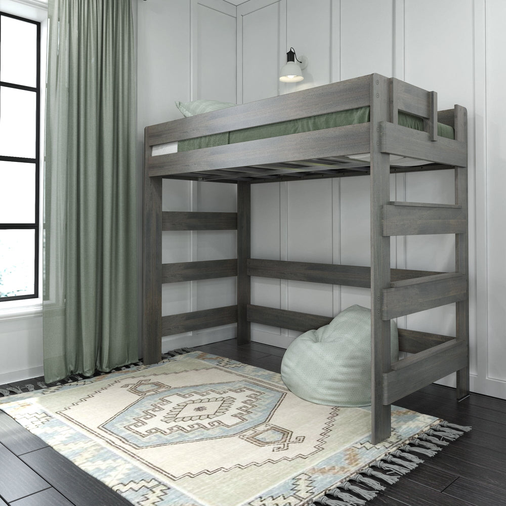 Max and Lily Modern Farmhouse Twin High Loft Bed in Driftwood - angled room view of the loft bed with a tall side ladder and full-length guardrails, styled with green curtains, a patterned rug, and a beanbag chair underneath.