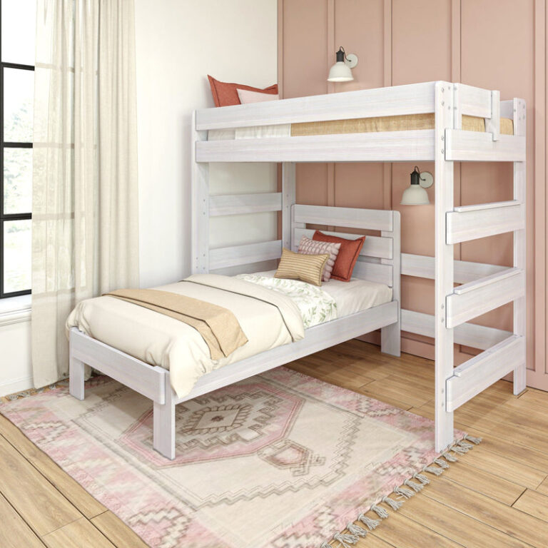 Max and Lily Modern Farmhouse Twin Over Twin L-Shaped Bunk Bed in White Wash - styled in a pink bedroom showing the upper bunk over a perpendicular lower twin bed with a side ladder and area rug.