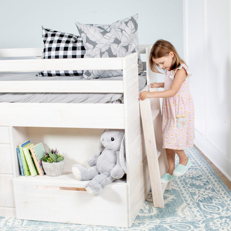 Max and Lily Solid Wood Play and Store Low Loft in White - a young girl climbing the ladder beside the open under-bed storage step holding books and a plush toy