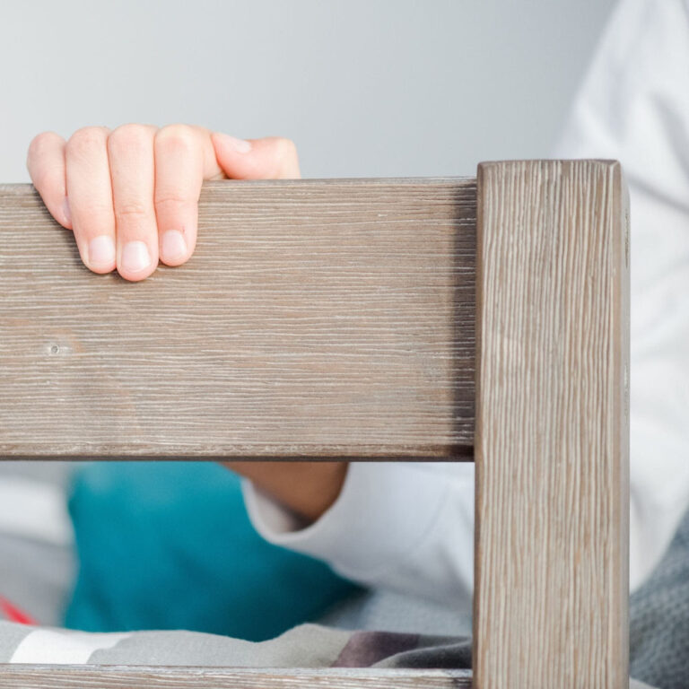 Max And Lily Twin High Loft Bed Clay Guardrail Detail Max and Lily Twin High Loft Bed in Clay - close-up of a child's hand gripping the solid wood guardrail, showing the finish's wood grain.