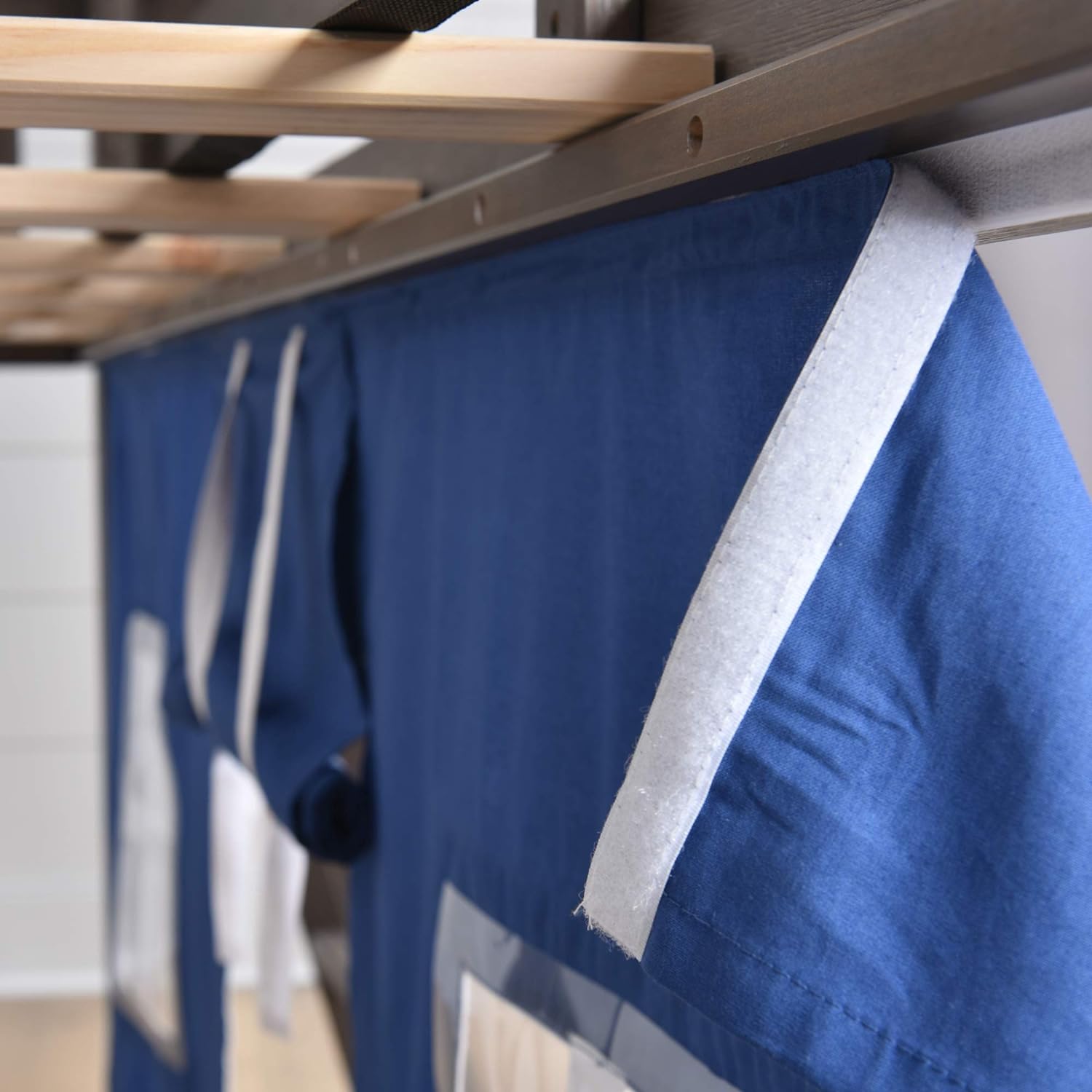 Max and Lily Twin Low Loft Bed - close-up of the white velcro strip attaching the blue play tent to the bed frame slats.