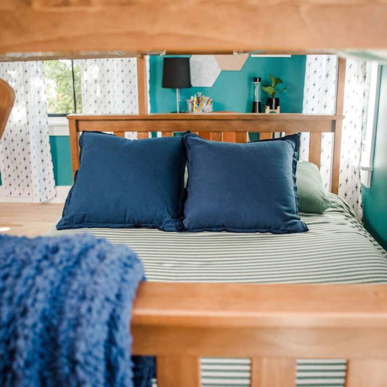 Max And Lily Twin Over Full Bunk Bed With Storage Pecan Lower Bunk Detail Max and Lily Twin Over Full Bunk Bed with Storage in Pecan - close view of the full-size lower bunk headboard and pillows beneath the top bunk