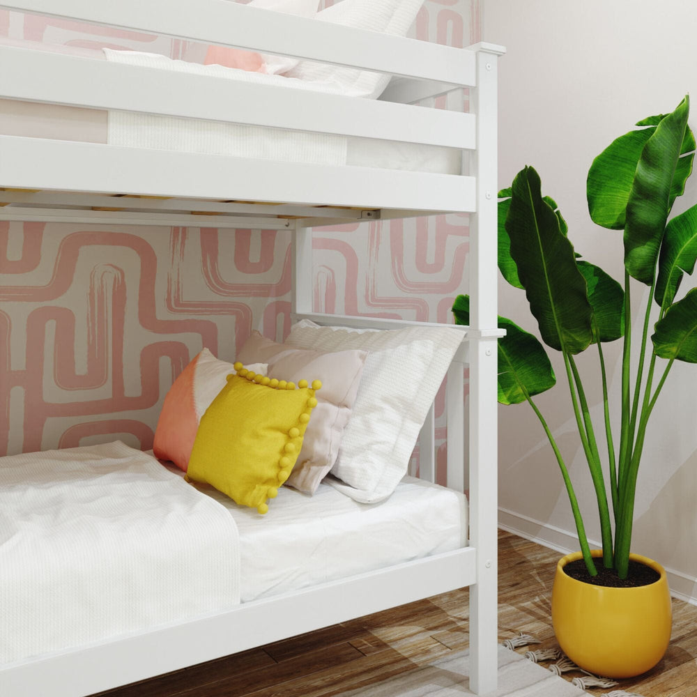 Max and Lily Twin Over Twin Bunk Bed with Ladder on End in White - close-up of the lower bunk with pillows and the corner post beside a potted plant