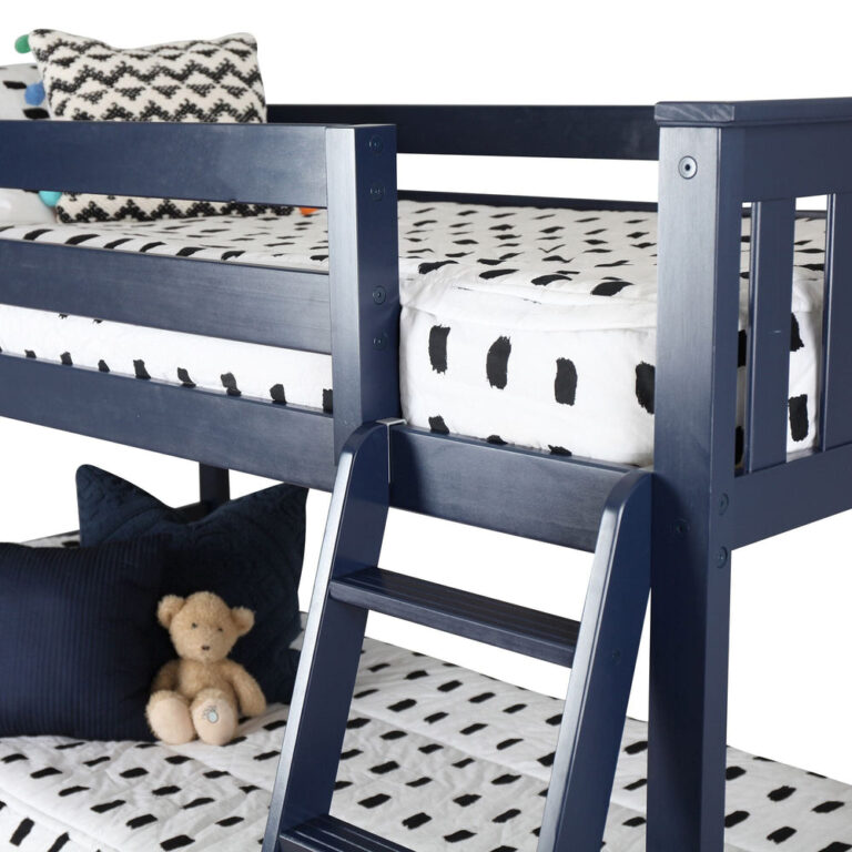 Max And Lily Twin over Twin Low Bunk Bed in Blue - closeup of the angled ladder, top bunk guardrail and slatted end panel with a teddy bear on the lower bunk