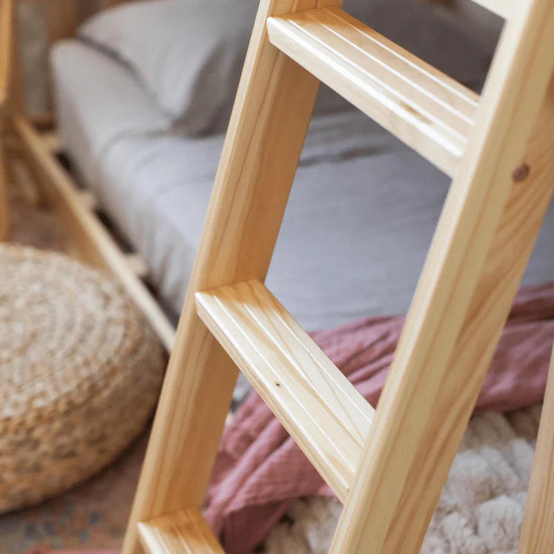 Max And Lily Twin over Twin Low Bunk Bed in Natural - closeup of the angled ladder's wide grooved steps beside the lower bunk