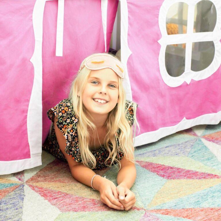Max And Lily Twin Over Twin Low Bunk Bed With Curtain Kids Playing 10 Max and Lily Twin Over Twin Low Bunk Bed With Curtain - young girl resting in front of the pink playhouse curtain with its arched window cutout