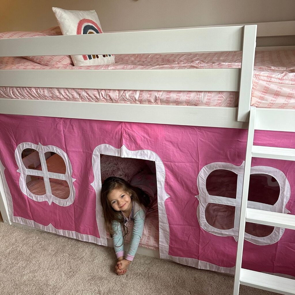 Max And Lily Twin Over Twin Low Bunk Bed With Curtain Kids Playing 12 Max and Lily Twin Over Twin Low Bunk Bed With Curtain - young girl peeking out from the doorway of the pink playhouse curtain beneath the top bunk
