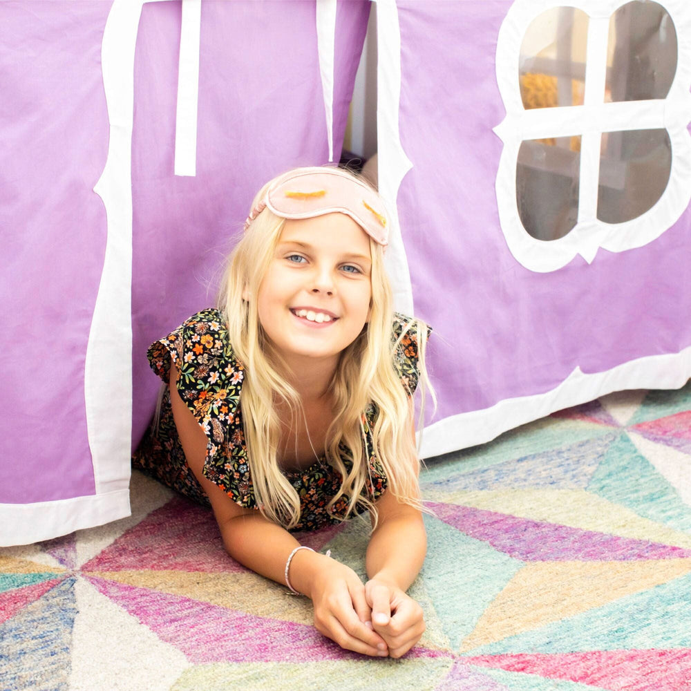 Max and Lily Twin Over Twin Low Bunk Bed With Staircase & Curtain in Clay Purple/White - a smiling child lying under the purple and white castle curtain tent.