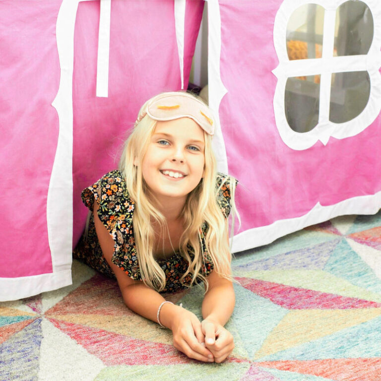 Max And Lily Twin Over Twin Low Bunk Bed With Staircase Curtain Grey Pink White Kids Playing Max and Lily Twin Over Twin Low Bunk Bed With Staircase & Curtain in Grey Pink/White - a smiling girl lying on the floor beneath the pink playhouse tent curtain.