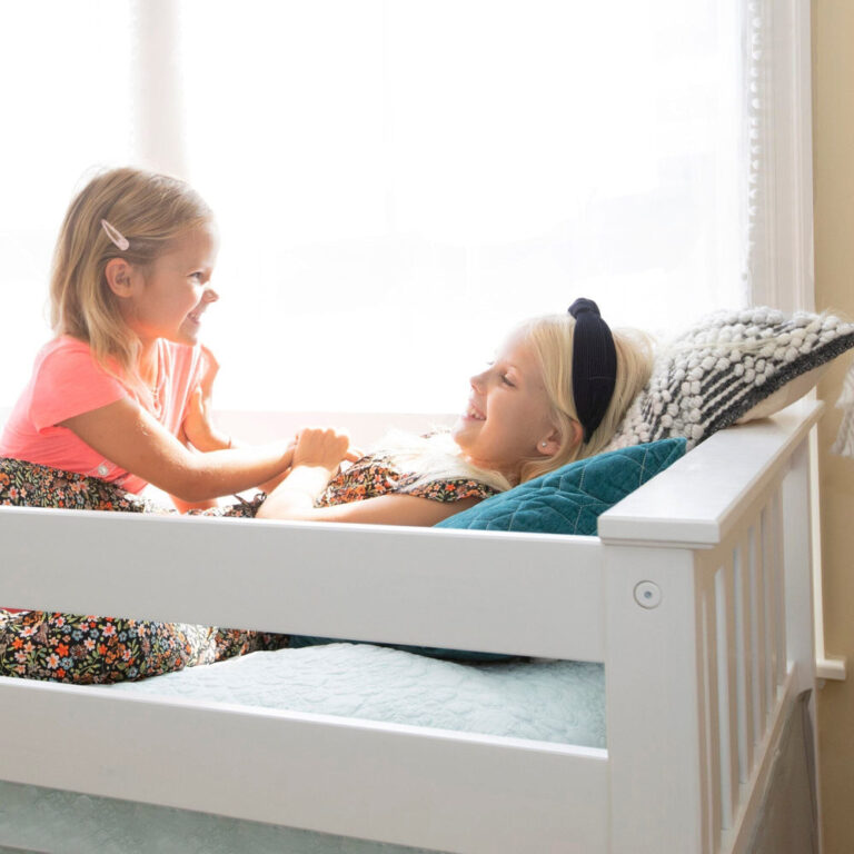 Max And Lily Twin Over Twin Low Bunk Bed With Staircase Curtain White Blue White Kids Playing Max and Lily Twin Over Twin Low Bunk Bed With Staircase & Curtain in White Blue/White - two children playing on the lower bunk beside a window with the safety guardrail in front