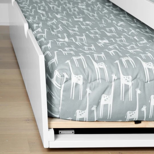 Max And Lily Twin Size Trundle Bed in White - trundle rolled out from under the bed with a giraffe-print mattress, wood slat and roller visible in a bedroom setting