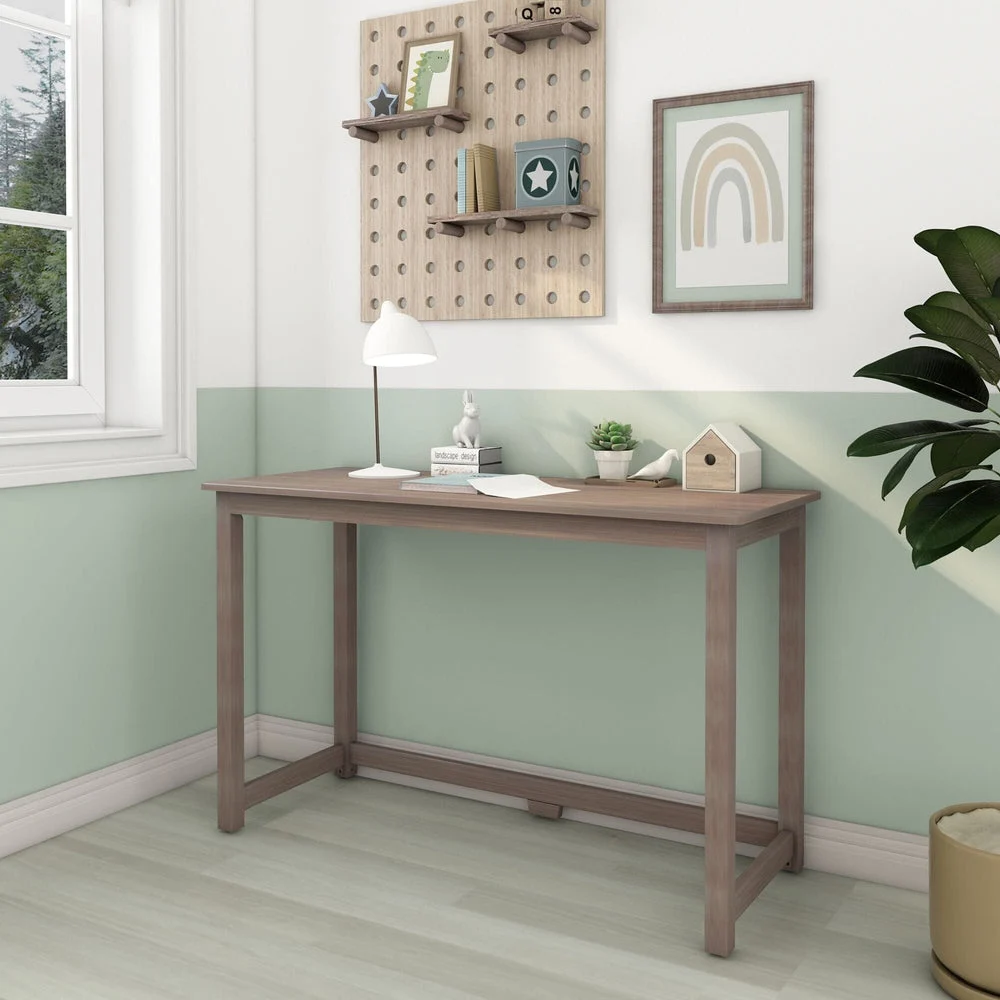 Max and Lily Writing Desk in Clay - angled view in a bright kids' room beside a window with pegboard shelving and decor.