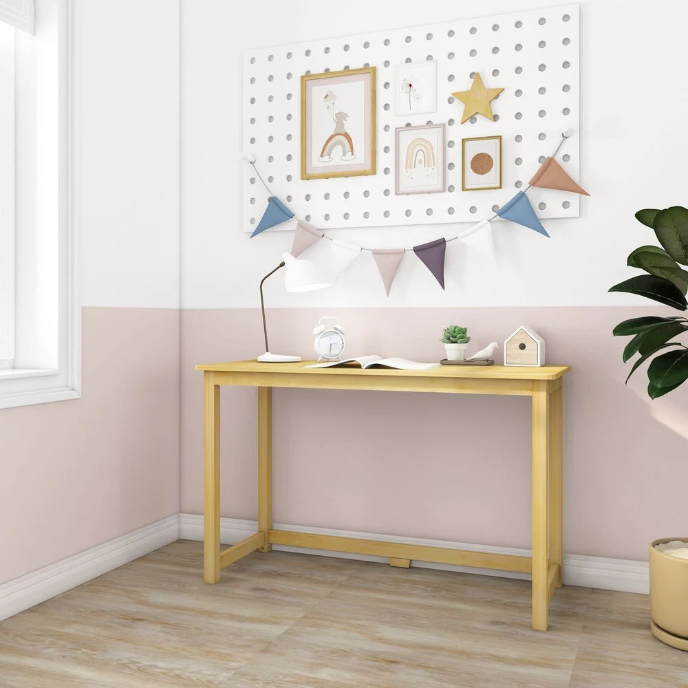 Max and Lily Writing Desk in Natural - angled view in a corner kids room with a window and pegboard gallery wall