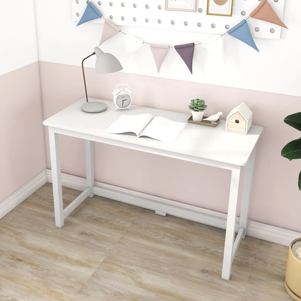 Max and Lily Writing Desk in White - styled in a pink kids room with a desk lamp, alarm clock, open book and potted plant on top