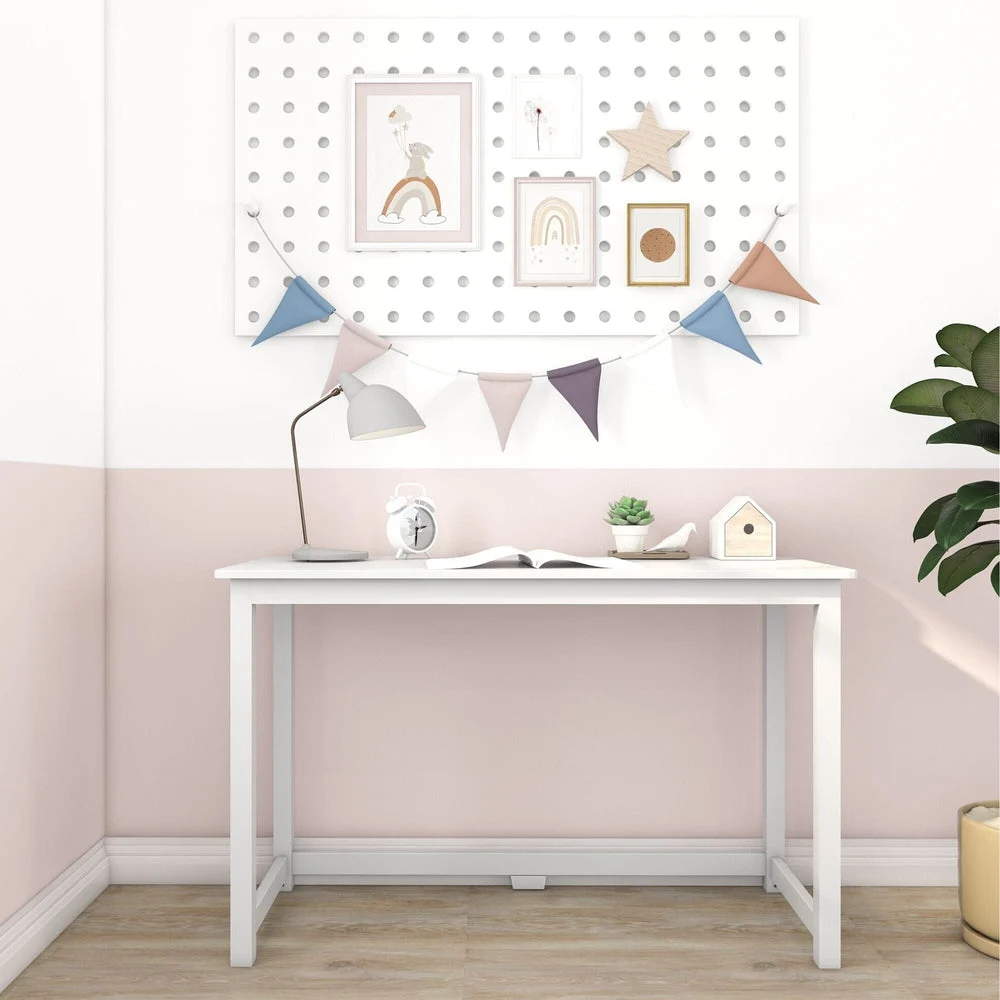 Max and Lily Writing Desk in White - shown front-on against a pink wall with a decorative pegboard, desk lamp and books