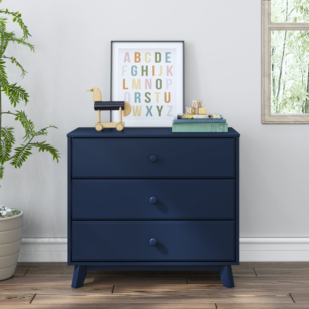 Max & Lily Classic 3 Drawer Dresser in Blue - shown front-on in a nursery with a potted plant, framed alphabet wall art, and stacked books on top.