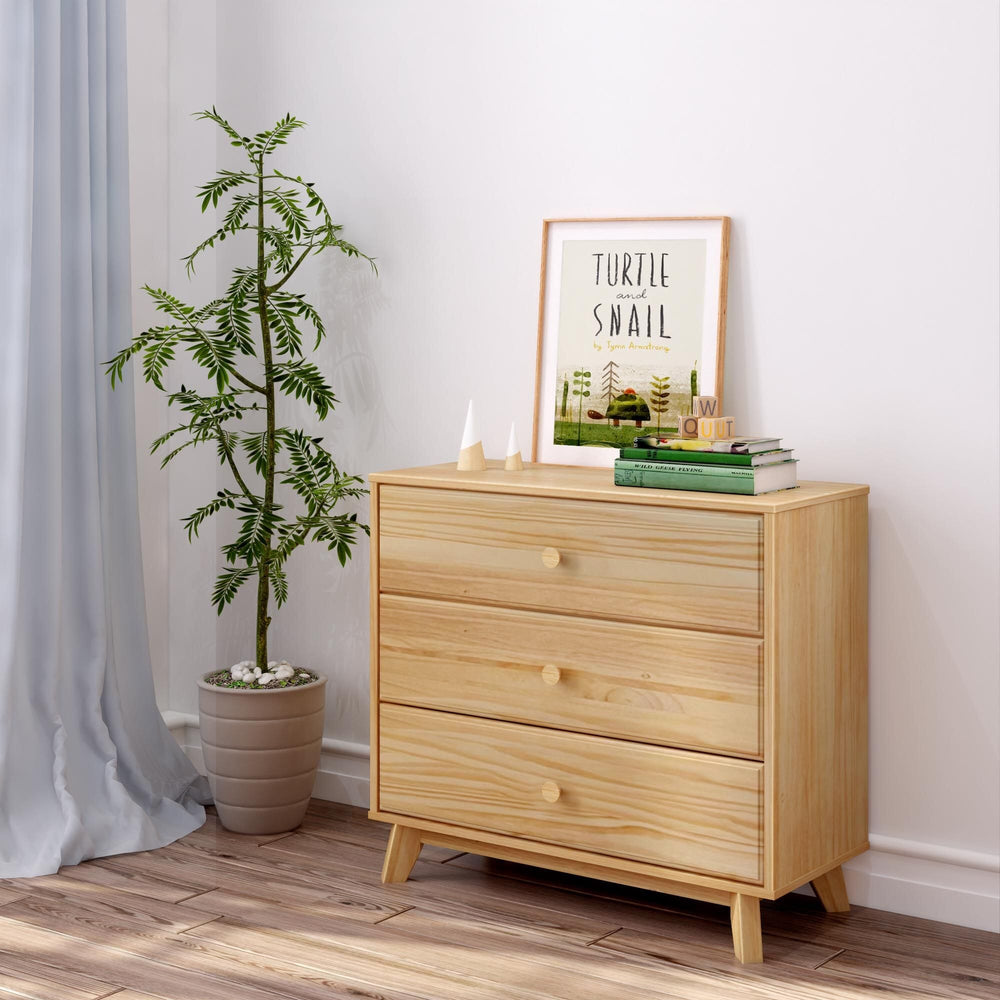 Max & Lily Classic 3 Drawer Dresser in Natural - styled in a bedroom beside a potted plant with framed art and books on top