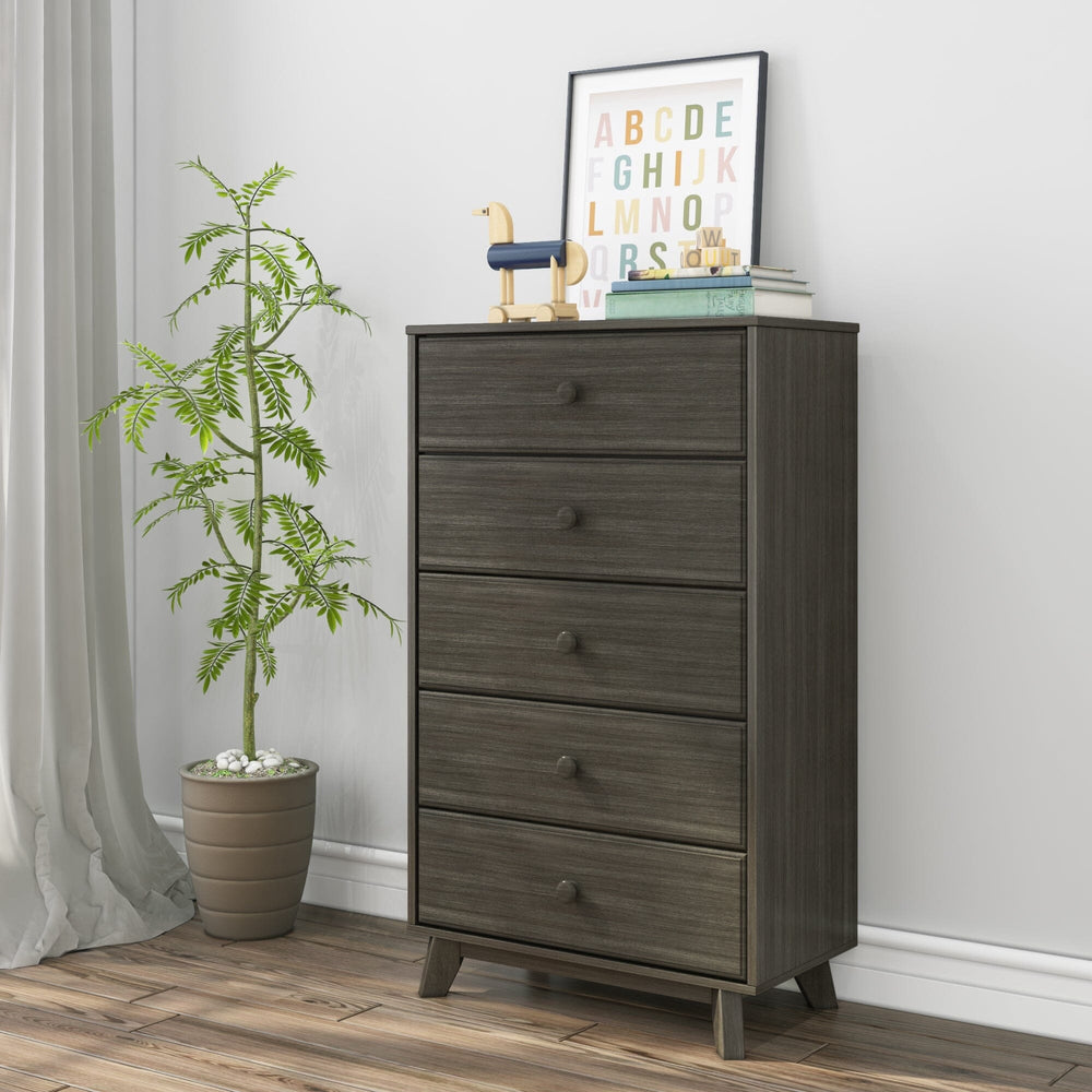 Max & Lily Classic 5 Drawer Dresser in Clay - angled view styled in a child's bedroom with a potted plant, a framed alphabet print, and wooden toys on top