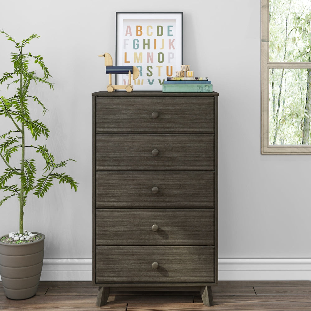 Max & Lily Classic 5 Drawer Dresser in Clay - front view in a bedroom setting beside a potted plant and window with a framed alphabet print and books on top