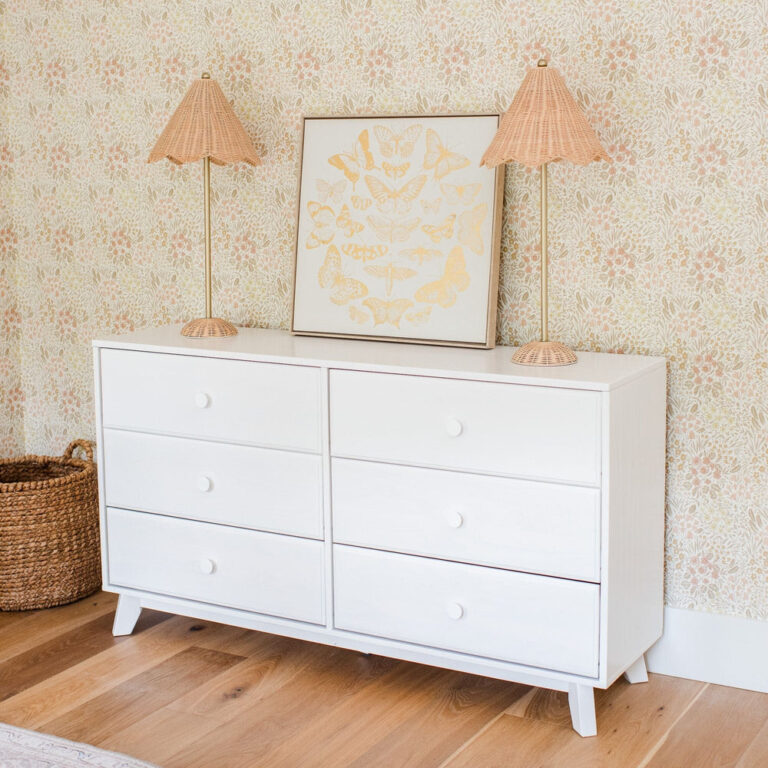 Max Lily Classic 6 Drawer Dresser White Room Scene Max & Lily Classic 6 Drawer Dresser in White - styled in a nursery with floral wallpaper, two rattan lamps, and framed butterfly wall art.