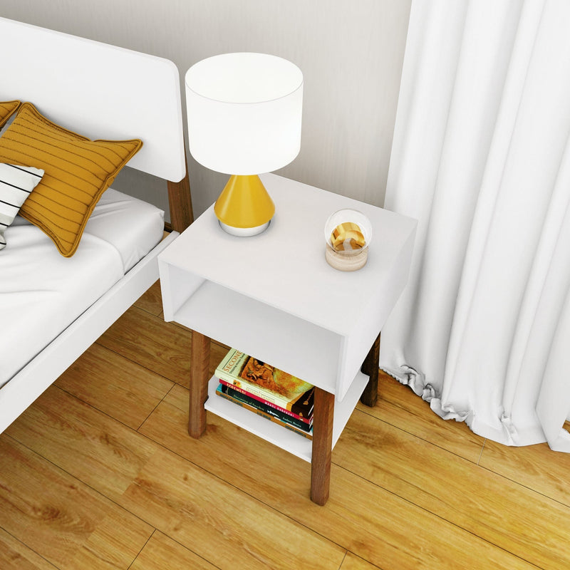 Max & Lily Mid-Century Modern Cubby Night Stand in White/Pecan - beside a bed with a lamp on top and books on the lower open shelf