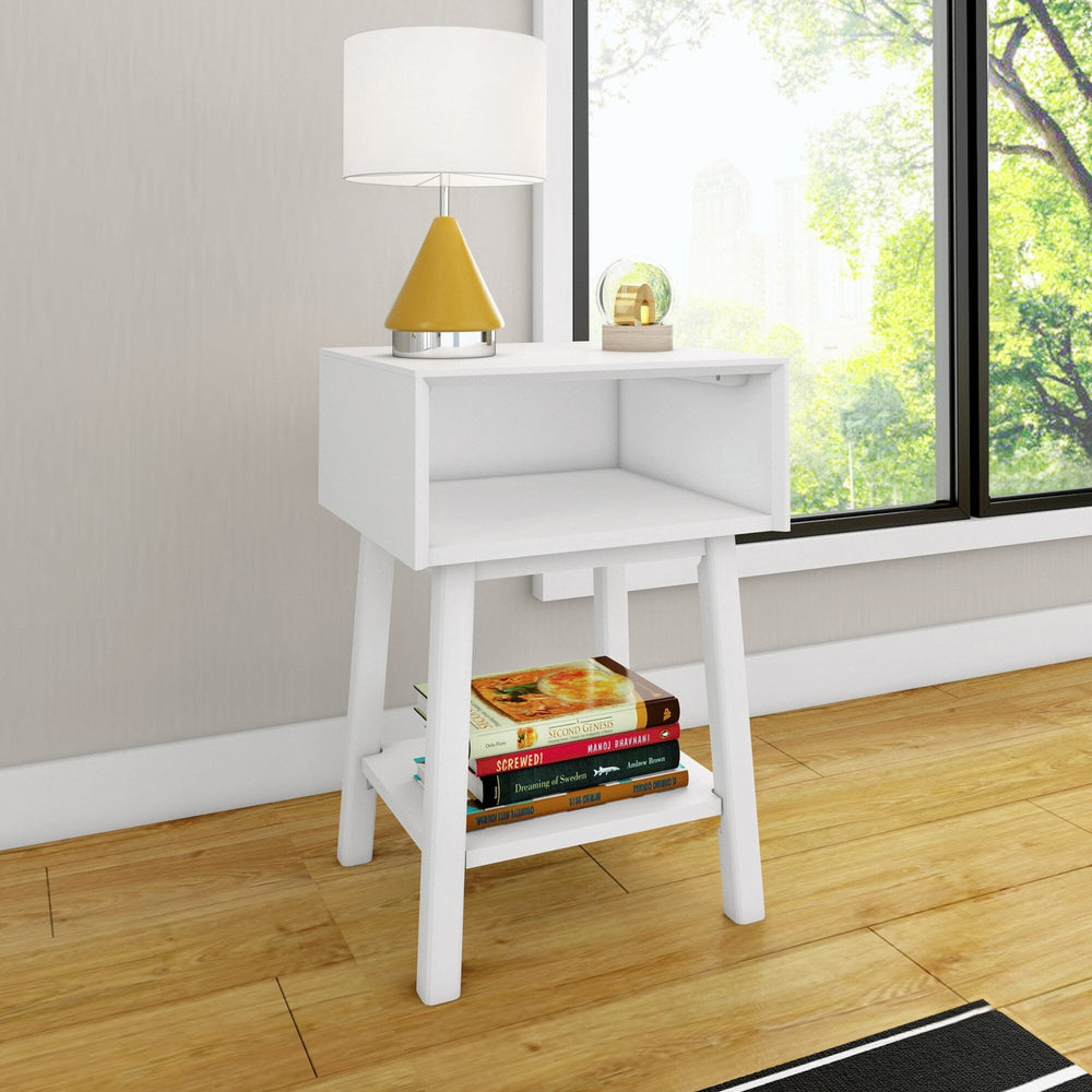 Max & Lily Mid-Century Modern Cubby Night Stand in White - styled beside a window with a table lamp and books stored on the open lower shelf.