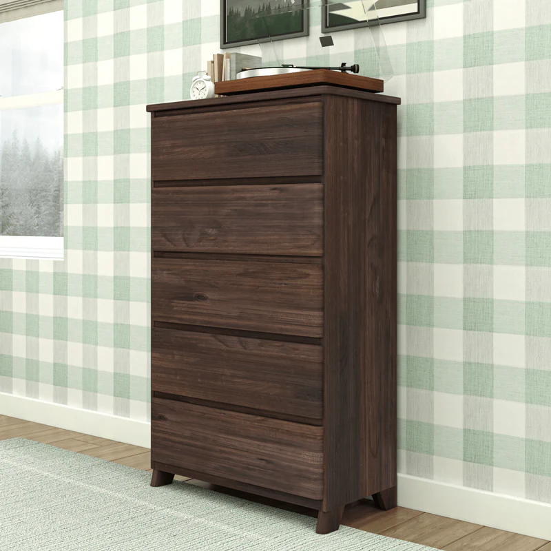 Max & Lily Modern Farmhouse 5 Drawer Dresser in Barnwood Brown - angled view in a bedroom beside a window with decor on top