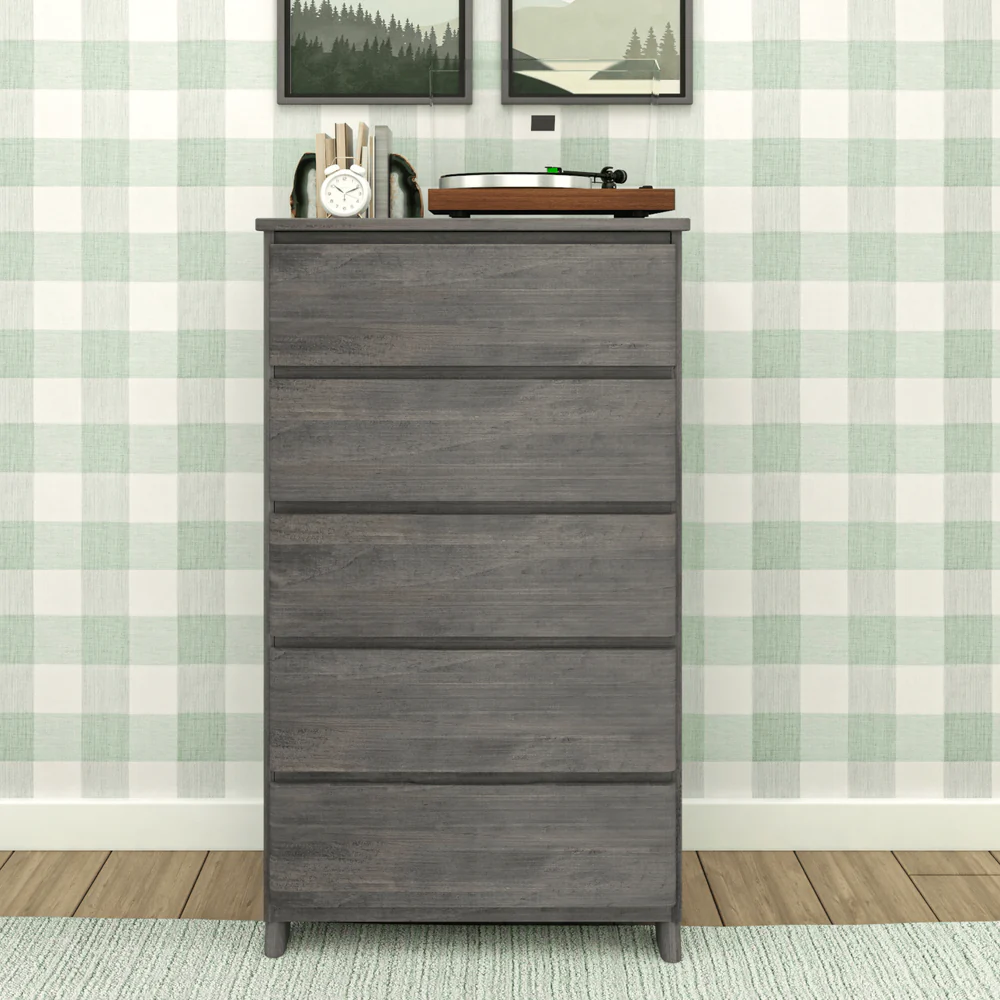 Max & Lily Modern Farmhouse 5 Drawer Dresser in Driftwood - front view in a bedroom with a turntable and framed art on top against plaid wallpaper