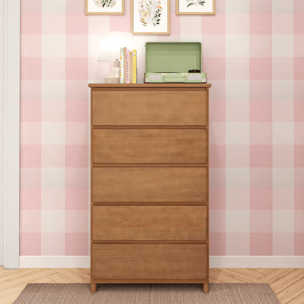 Max & Lily Modern Farmhouse 5 Drawer Dresser in Pecan - front view styled in a bedroom with a record player and books on top against pink gingham wallpaper.