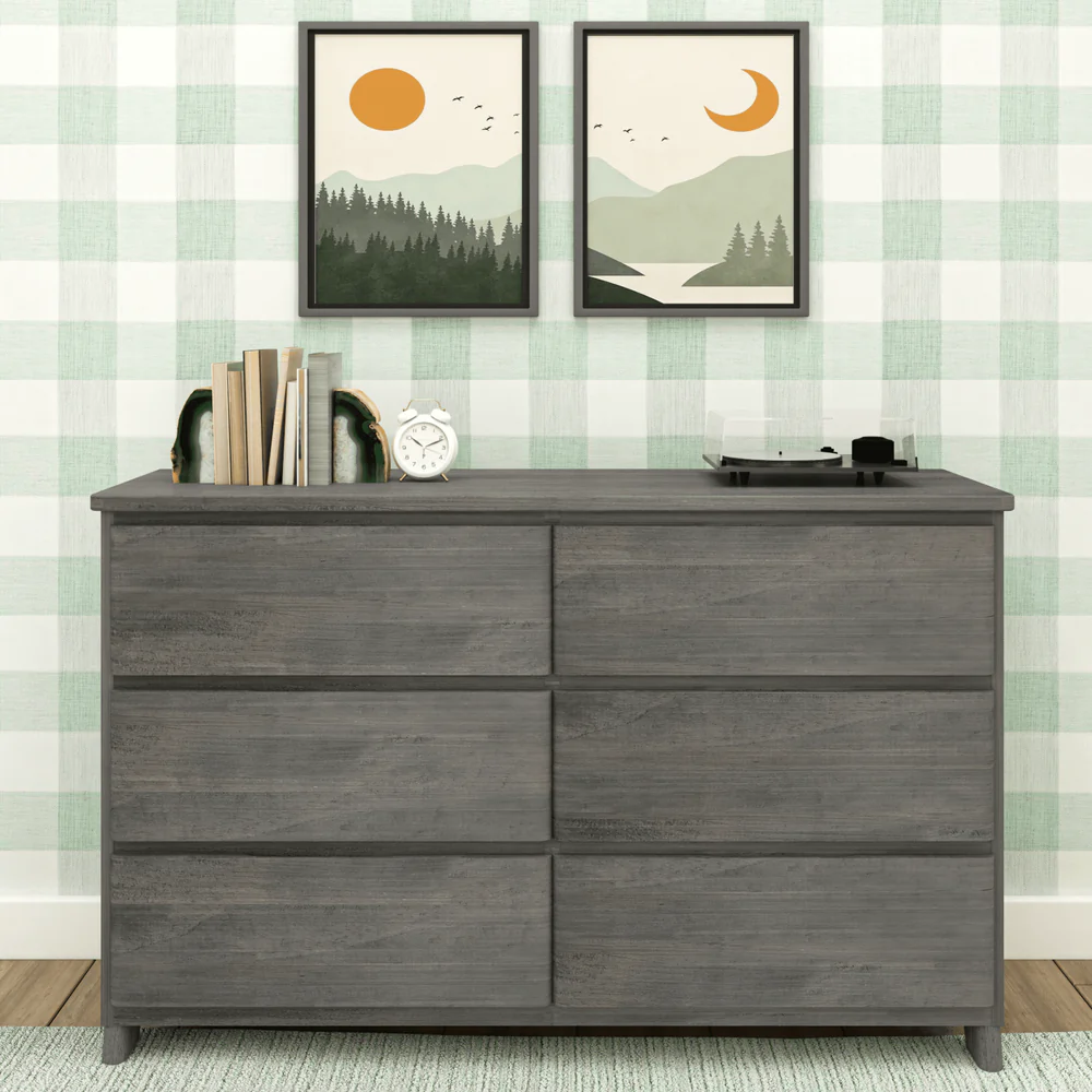 Max & Lily Modern Farmhouse 6 Drawer Dresser in Driftwood - styled in a bedroom with books, a clock and a record player on top beneath framed landscape art.