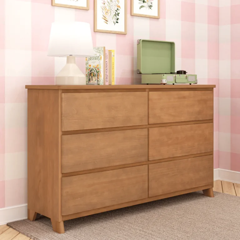 Max Lily Modern Farmhouse 6 Drawer Dresser Pecan Angle View 2 Max & Lily Modern Farmhouse 6 Drawer Dresser in Pecan - angled view styled in a bedroom with a lamp, books, and record player against a pink checkered wall.