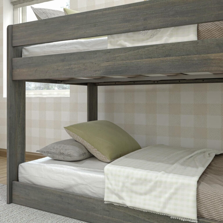 Max & Lily Modern Farmhouse Twin Over Twin Low Bunk Bed in Driftwood - close-up of the upper bunk safety guardrail and the lower bunk with pillows and a throw.