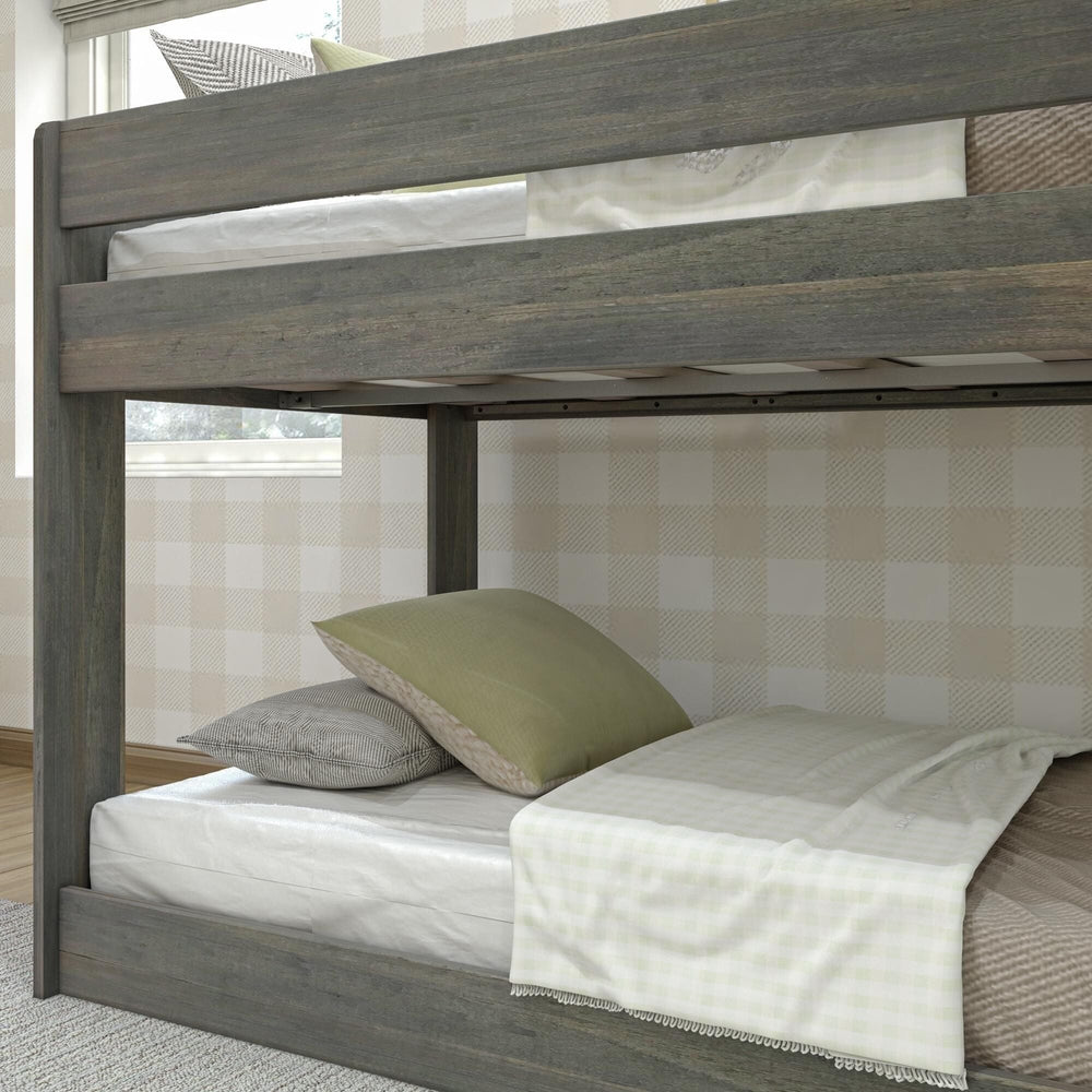 Max & Lily Modern Farmhouse Twin Over Twin Low Bunk Bed in Driftwood - close-up of the upper bunk safety guardrail and the lower bunk with pillows and a throw.