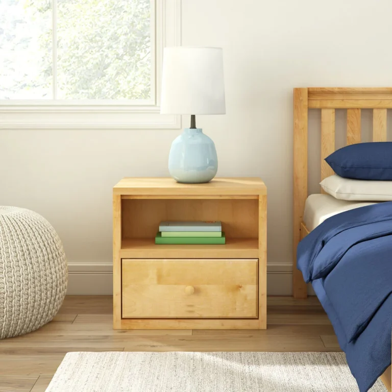 Maxtrix 1 Drawer Nightstand in Natural - front view in a bedroom next to a bed, with a lamp on top and books stored in the open shelf above the drawer