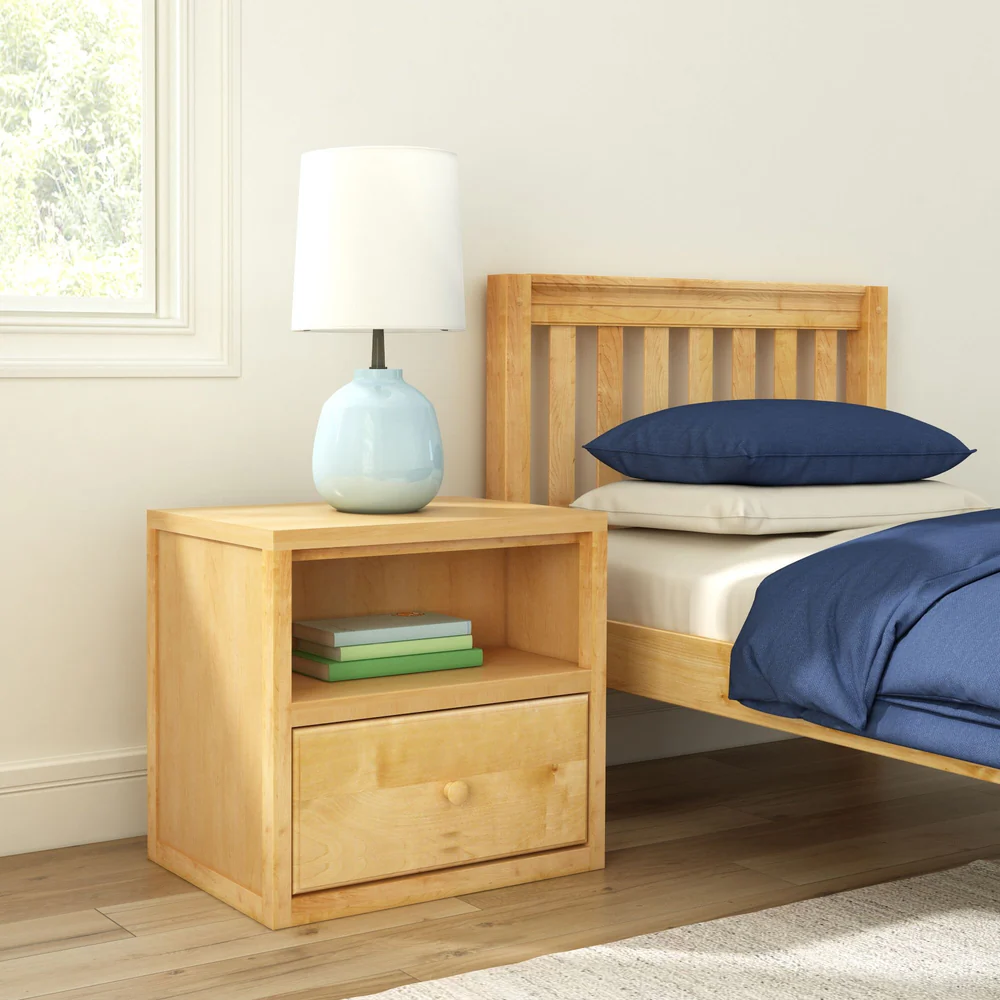 Maxtrix 1 Drawer Nightstand in Natural - angled bedroom scene with the nightstand beside a slatted headboard bed, holding a lamp and books on its open shelf
