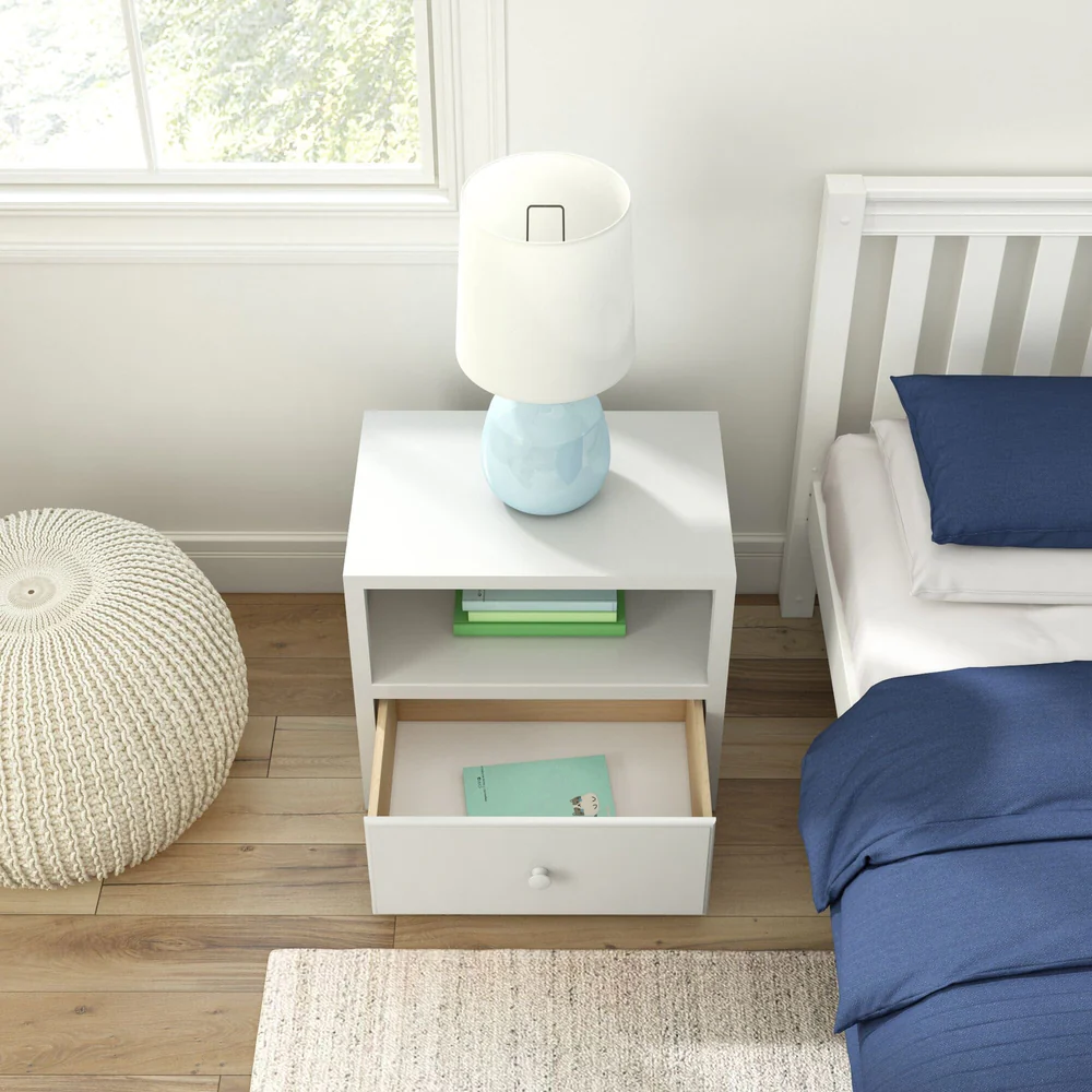 Maxtrix 1 Drawer Nightstand in White - overhead bedroom view with the drawer open holding a book, a lamp and books on the shelf, next to a bed with navy bedding