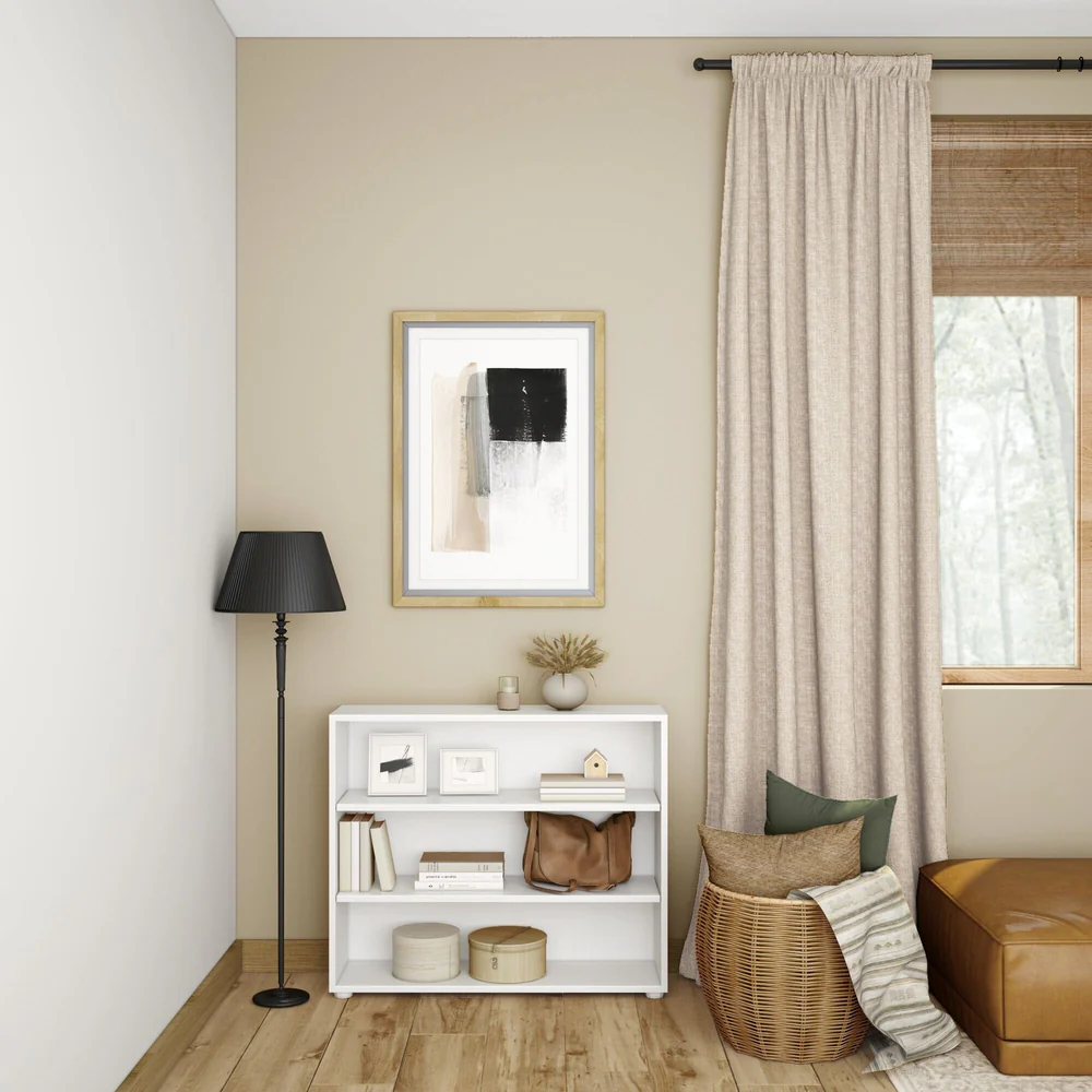 Maxtrix 3 Shelf Bookcase in White - styled in a living room holding books, framed prints and a satchel beside a floor lamp and curtained window