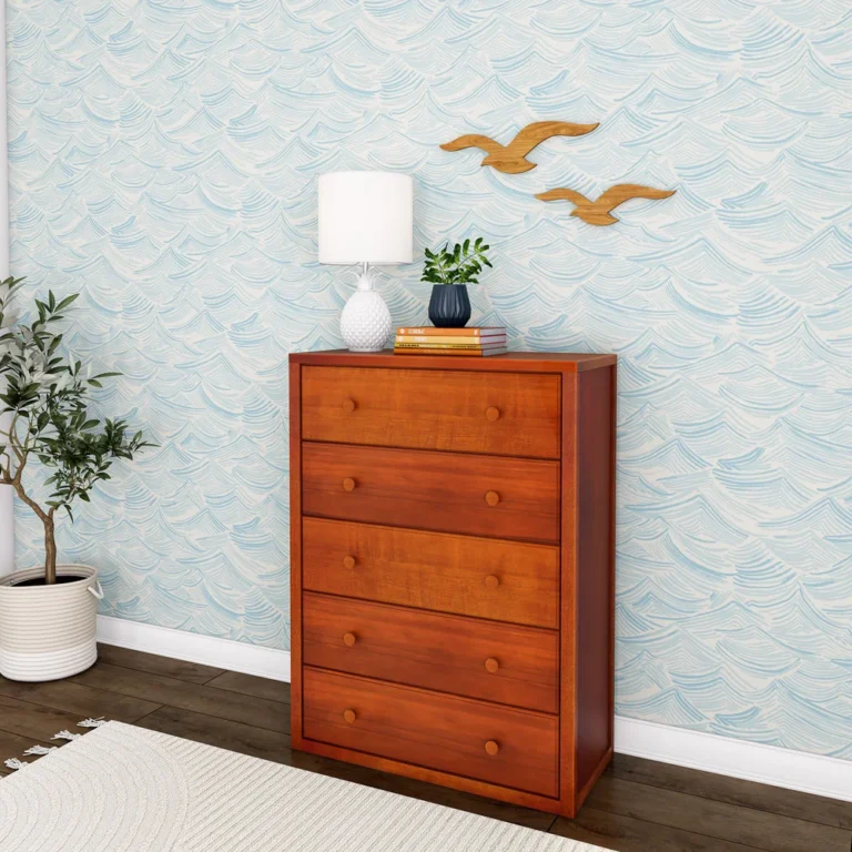 Maxtrix 5 Drawer Dresser Chestnut Angle Room Scene 1 Maxtrix 5 Drawer Dresser in Chestnut - angled view in a kids bedroom with wave-pattern wallpaper, styled with a lamp, plant and books on top