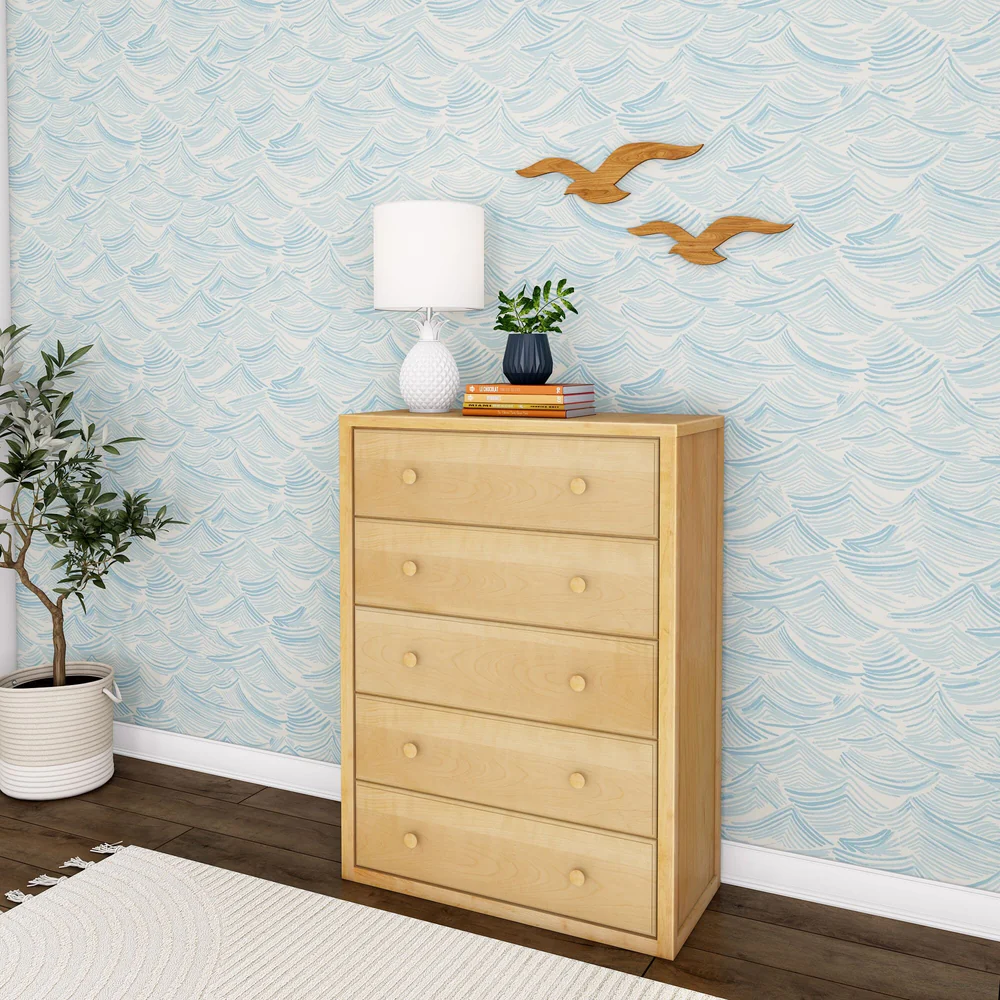 Maxtrix 5 Drawer Dresser Natural Angle Room Scene Maxtrix 5 Drawer Dresser in Natural - angled view in a styled bedroom with wave-print wallpaper, a lamp, plant and books on top