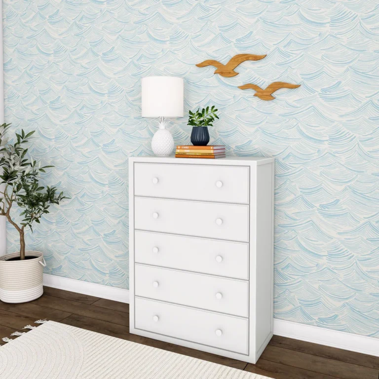 Maxtrix 5 Drawer Dresser White Room Scene Maxtrix 5 Drawer Dresser in White - angled view of the tall five-drawer dresser styled in a kids bedroom with a lamp, plant and books on top against wave-print wallpaper